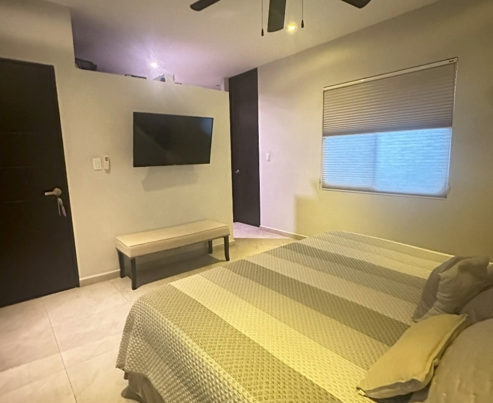 una recamara con una tv y un ventilador de techo en playa magna playa del carmen