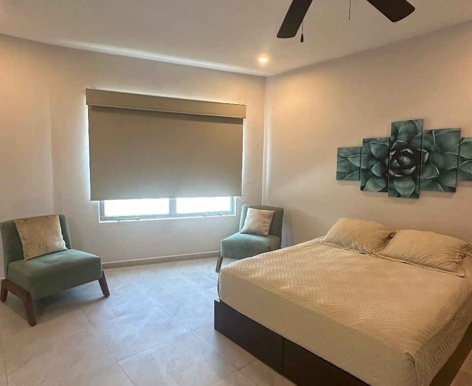 una recamara con cama queen size y cuadros decorativos en playa magna playa del carmen