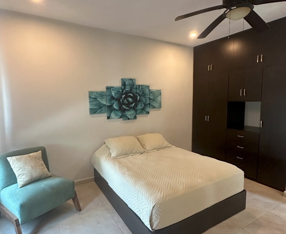 una recamara con closets de madera y un ventilador de techo en playa magna playa del carmen