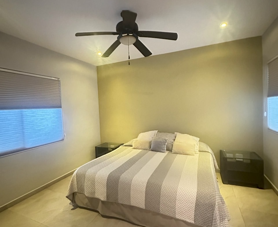 una recamara con cama matrimonial y un ventilador de techo en playa magna playa del carmen