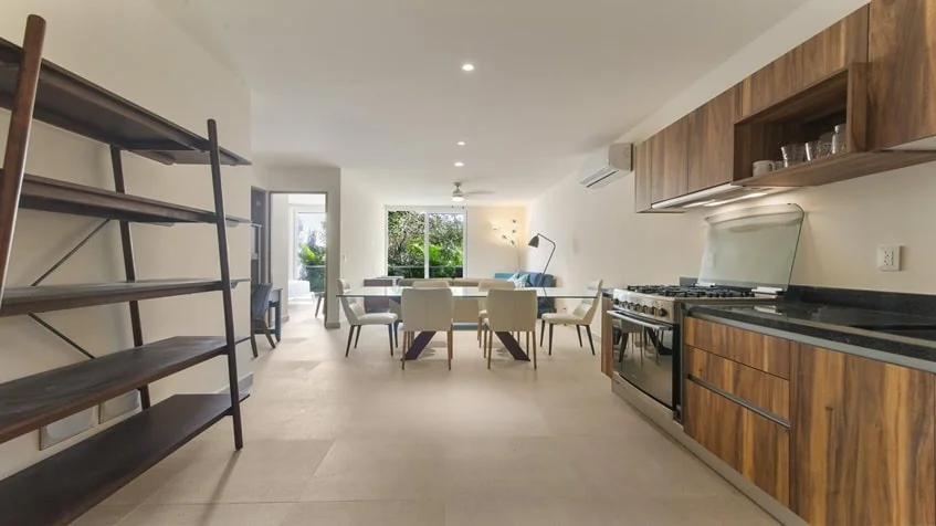 una cocina elegante con acabados de madera y un comedor al fondo en Santamar Akumal