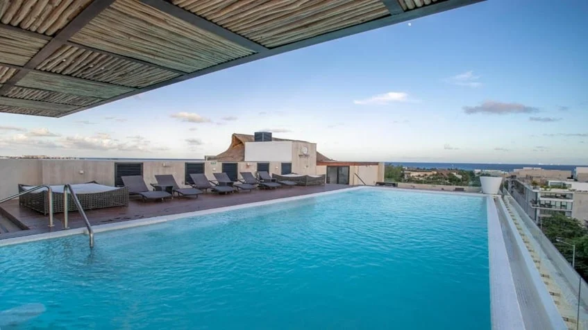 una piscina con camastros y vista al mar en macondo playa del carmen