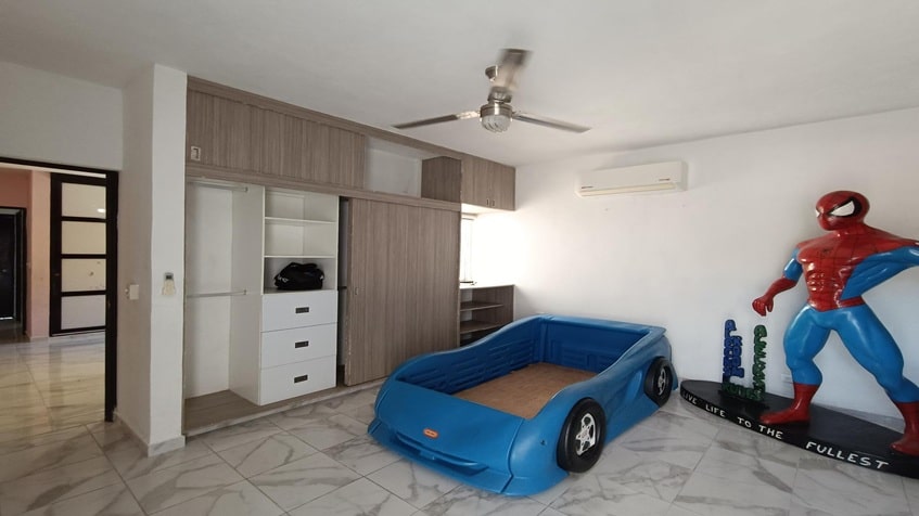 una recamara infantil con una cama en forma de coche y un closet de madera grande en santa fe del carmen