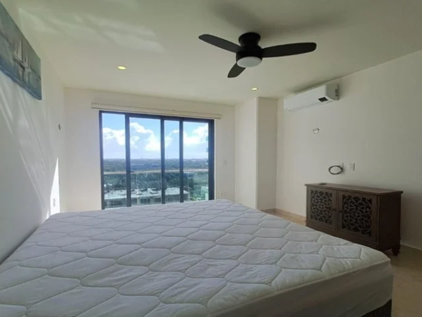 una recamara king size con un ventilador de techo y una ventana con vista al exterior en valle aurora playa del carmen