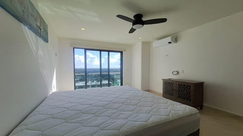 una recamara king size con un ventilador de techo y una ventana con vista al exterior en valle aurora playa del carmen