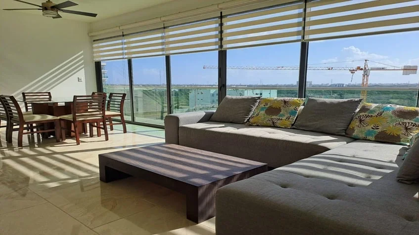 una sala, un comedor y una ventana grande en valle aurora playa del carmen