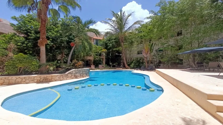una piscina refrescante con areas verdes en condominio bugambilias playa del carmen