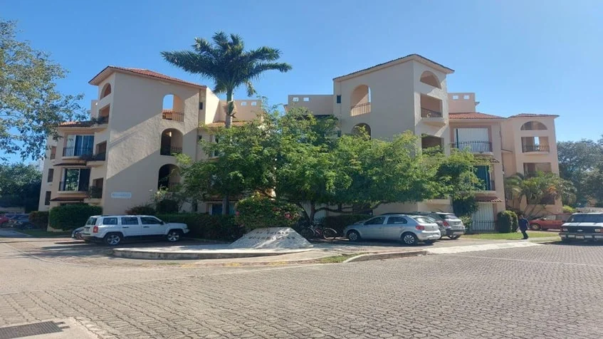 una fachada de un edificio de departamentos con un estacionamiento en condominio bugambilias playa del carmen