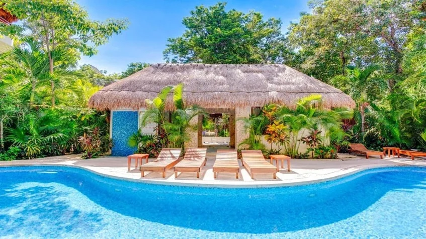 una palapa con areas verdes alrededor y una piscina para residentes en puerta zama tulum