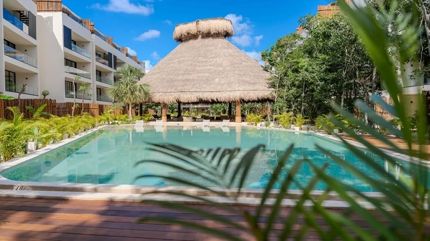 una alberca con palapa y areas verdes en samsara tulum