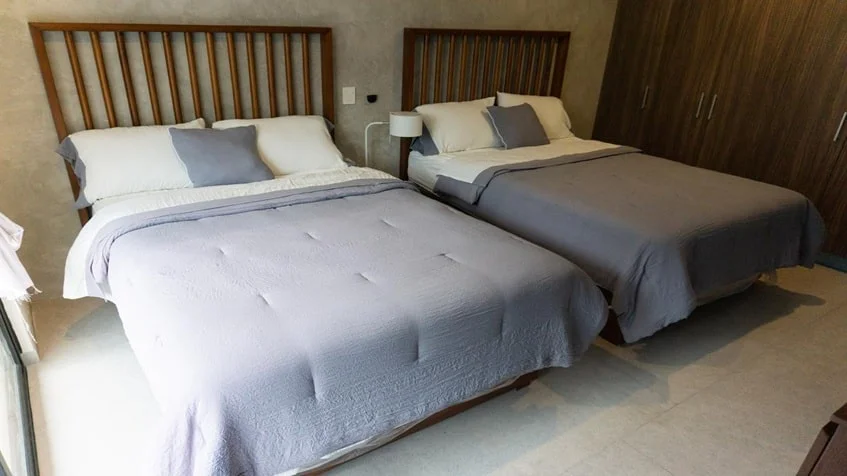 una recamara con 2 camas y un closet grande de madera en urban towers playa del carmen