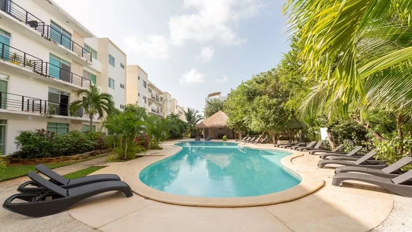 una alberca comun para residentes con camastros alrededor y una palapa en punta estrella playa del carmen