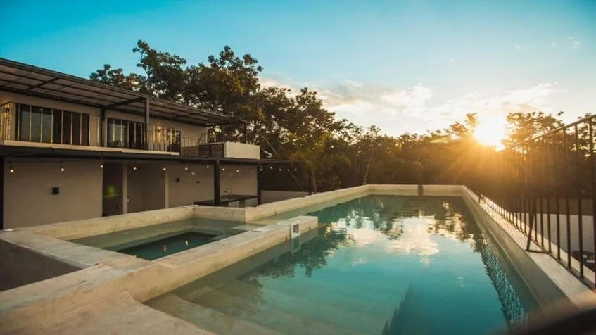una alberca con una puesta del sol en kantuun tulum