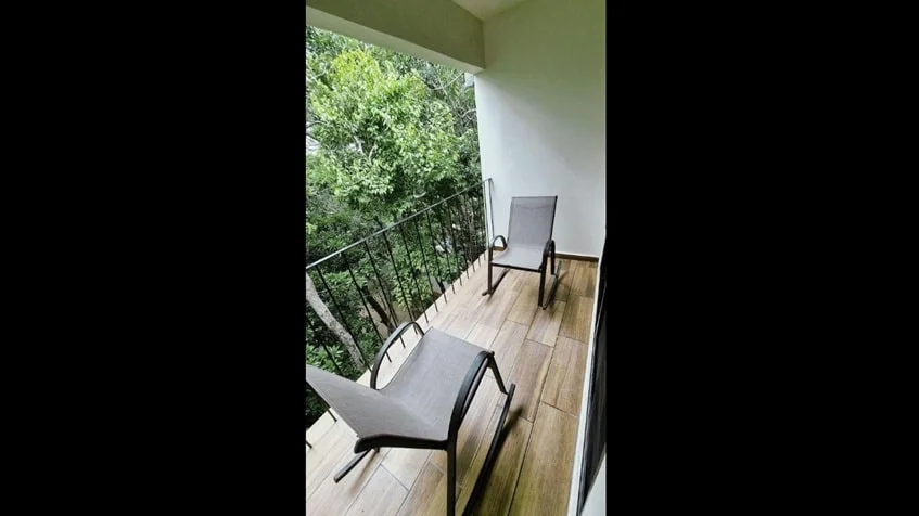 un balcon con 2 sillas y vista al jardin en kantuun tulum