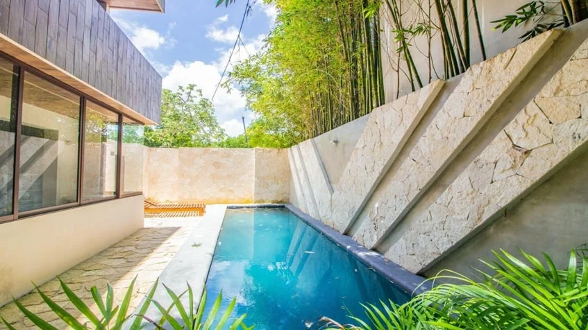 una piscina refrescan con areas verdes alrededor en verandas condos playa del carmen