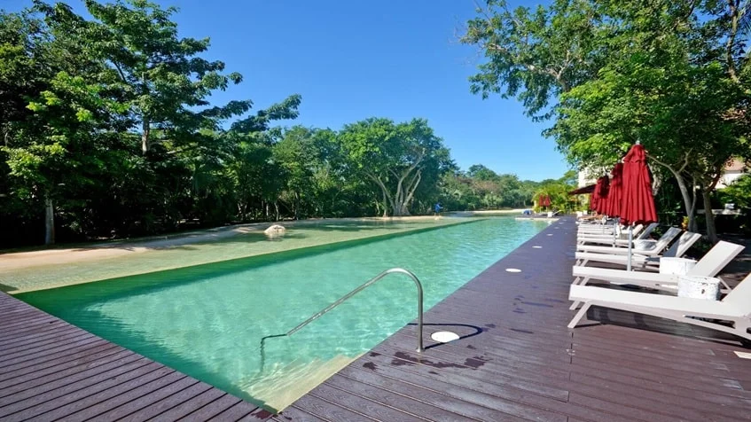 una alberca con varios camastros y sombrillas en lorena ochoa residences playa del carmen