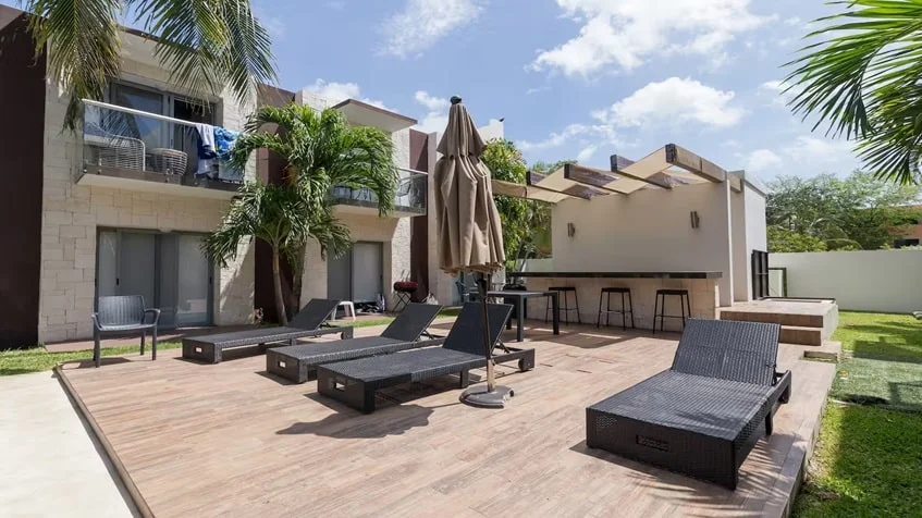 un area de camastros con sombrillas y un area lounge en condominio akab playacar