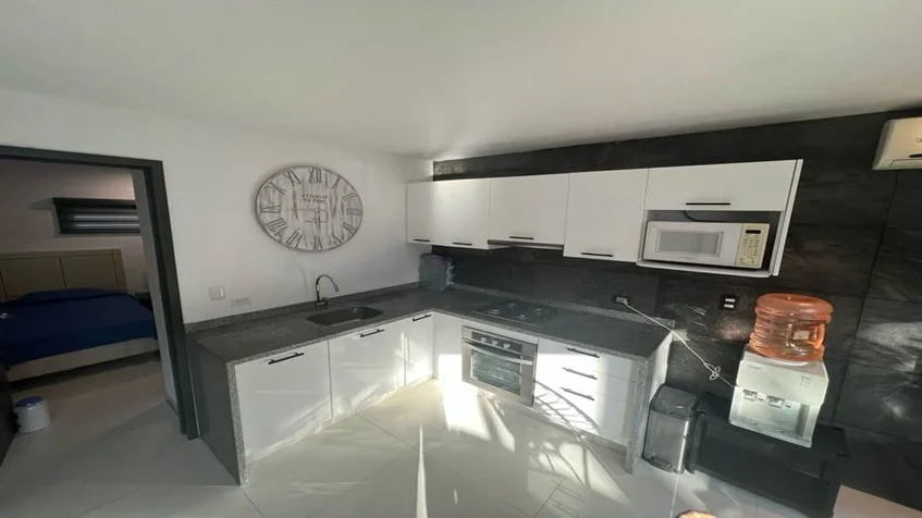 una cocina equipada con una parrilla electrica, un horno y una tarja de lavado en condominio anemonas playacar