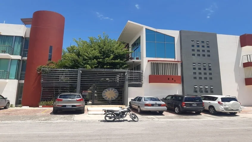 una fachada exterior con un estacionamiento amplio en edificio palmeiras playa del carmen