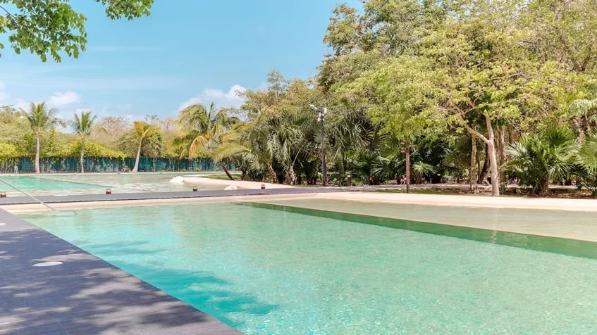 una alberca grande con multiples areas verdes alrededor en lorena ochoa residences playa del carmen