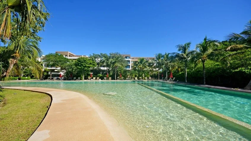 una alberca con un canal de nado y areas verdes alrededor en lorena ochoa residences playa del carmen