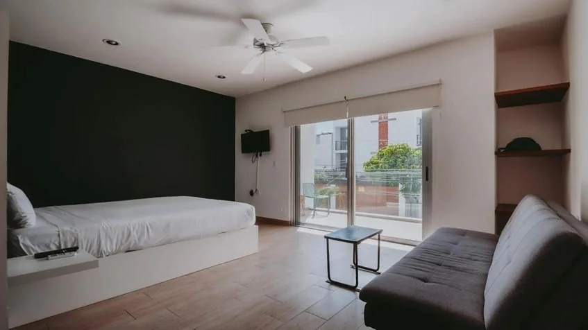 una recamara con un balcon y vista a la calle en casa mora suites playa del carmen
