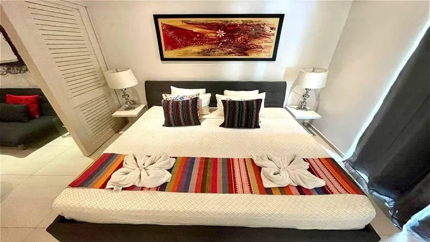 una cama king size, un cuadro decorativo y una lampara en condominio akab playacar