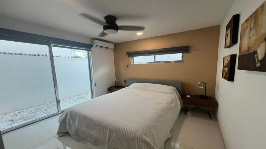 una cama matrimonial, un patio privado y un ventilador en condominio anemonas playacar