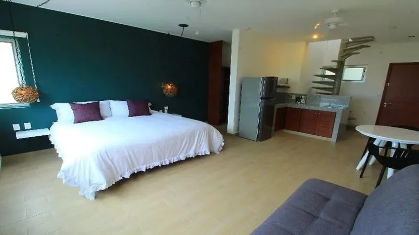 una recamara amplia, un sofa cama y unas escaleras en casa mora suites playa del carmen