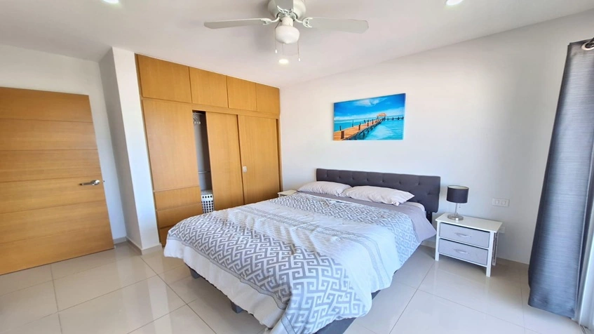 una recamara con un closet de madera grande, un cuadro decorativo y una cama matrimonial en yaakun condos playa del carmen