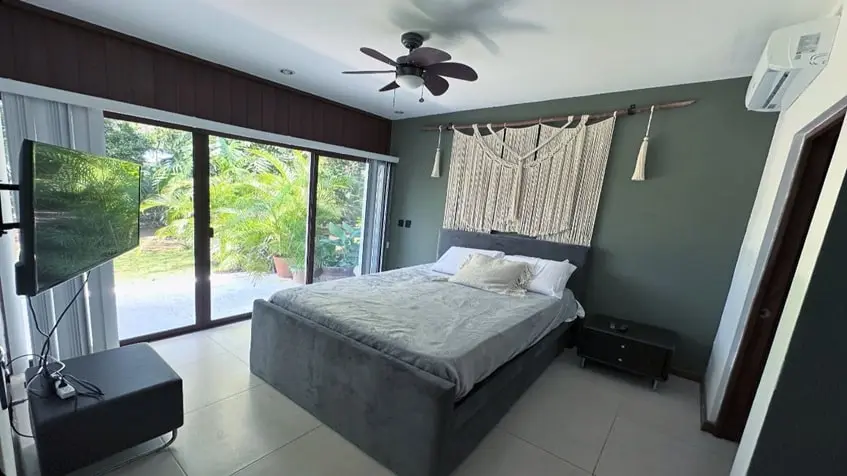 una recamara principal con un ventilador de techo, un aire acondicionado y una tv en golf drive playacar