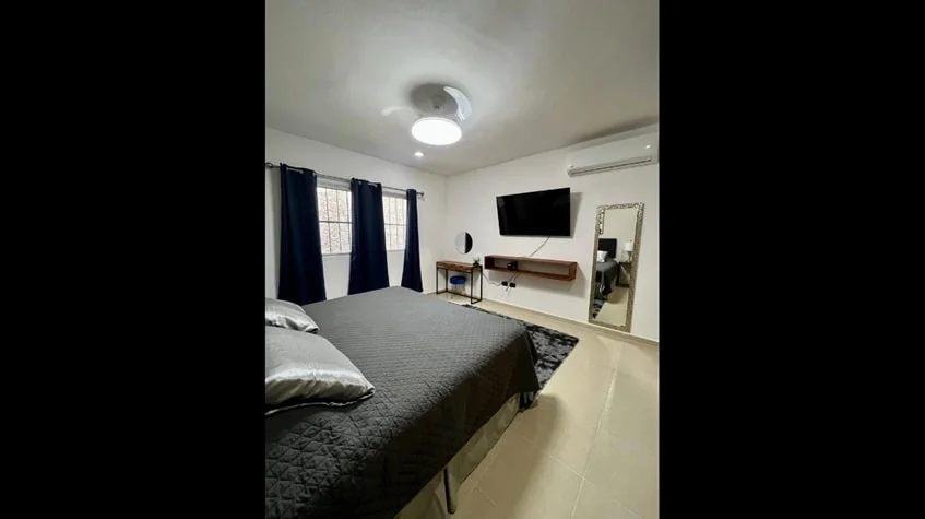 una cama matrimonial con una tv y un aire acondicionado en condominio alegro playa del carmen