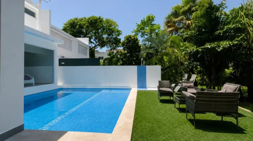 una piscina con areas verdes alrededor y unas sillas en club real playacar playa del carmen