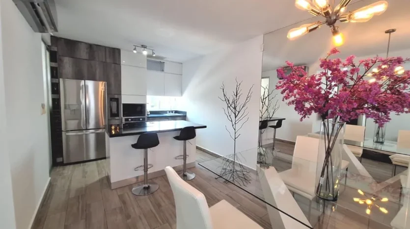 un comedor de cristal con una cocina equipada al lado en punta estrella playa del carmen